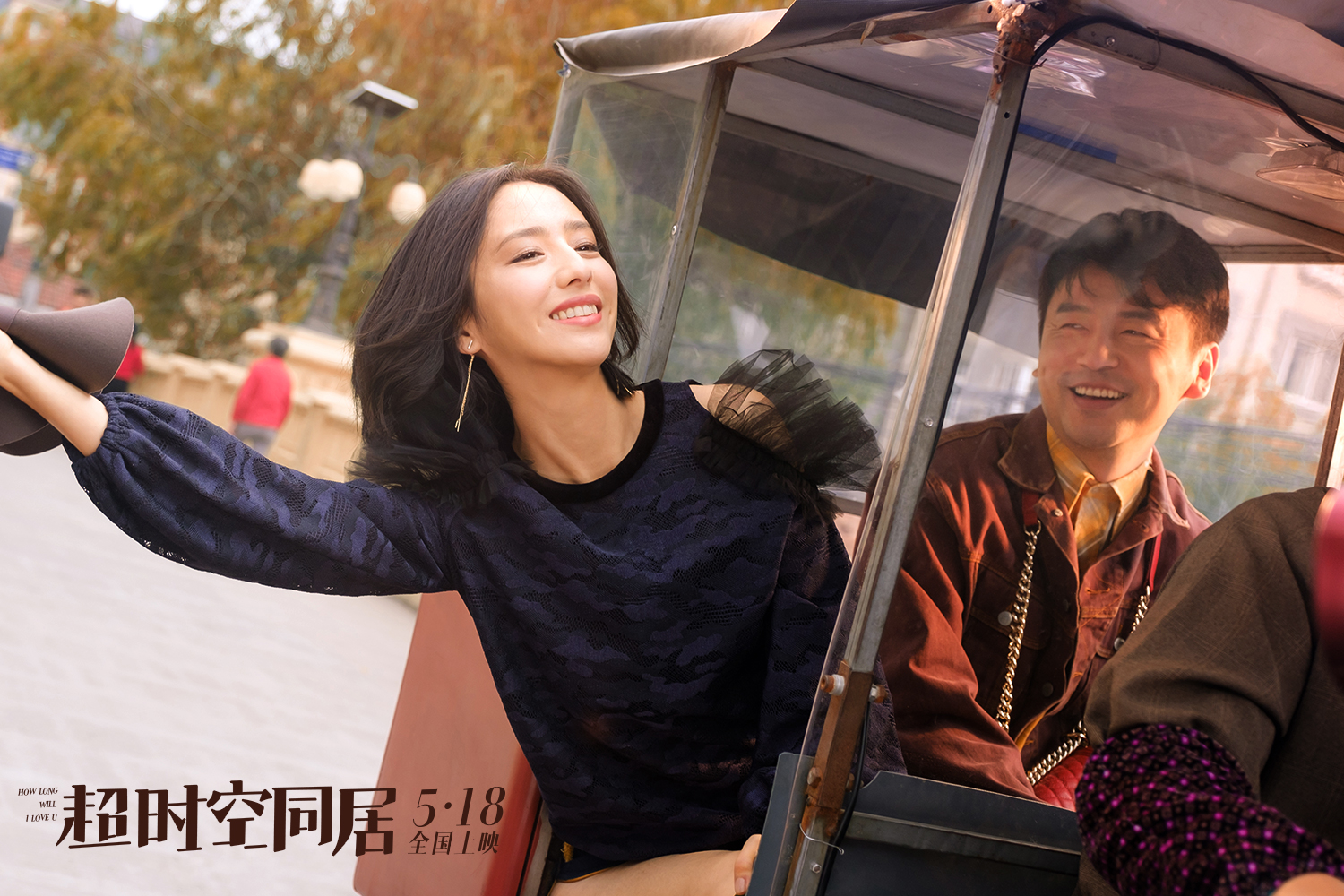 A smiling woman leans out of a buggy next to a smiling man