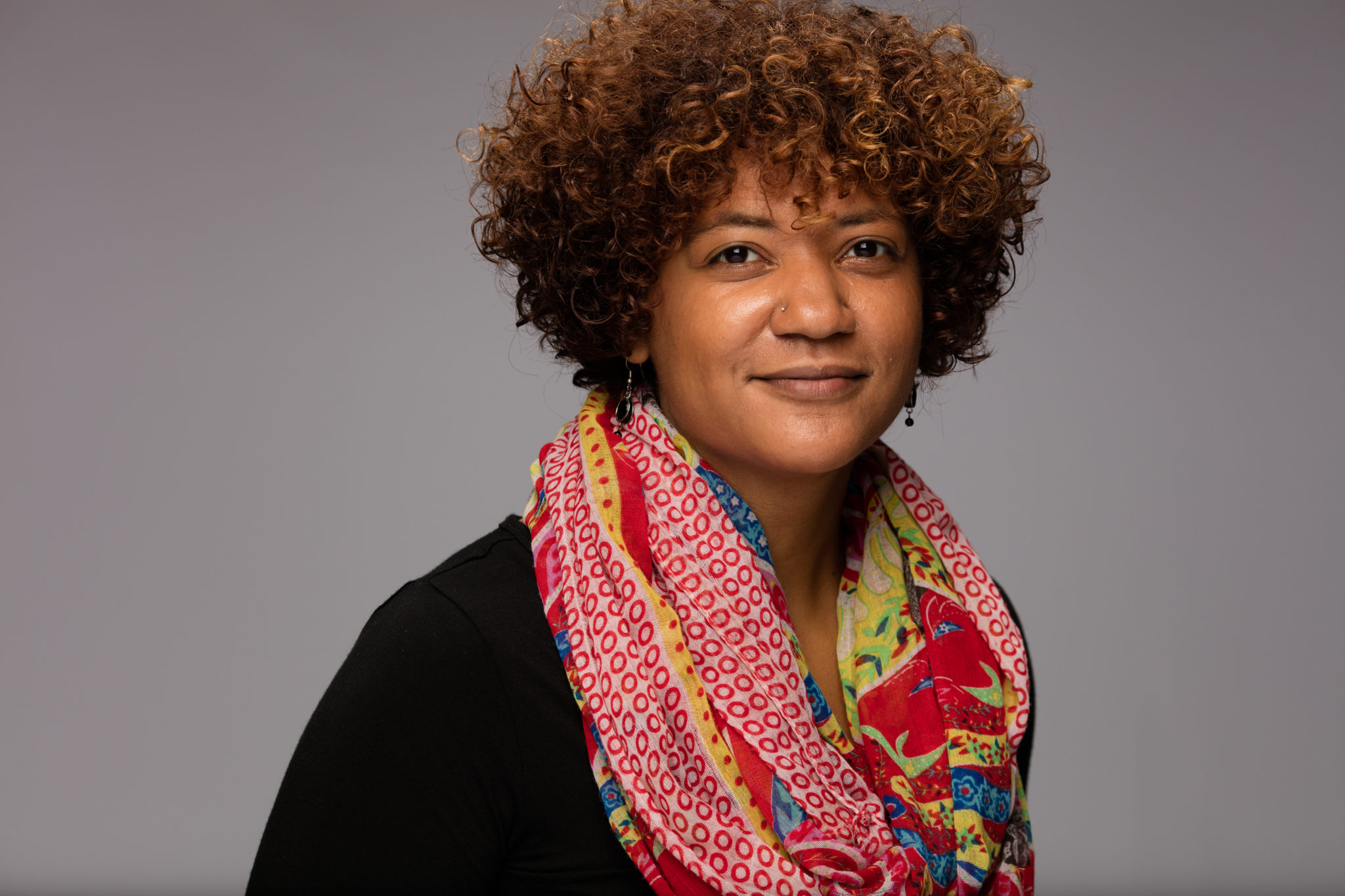 Headshot of a woman wearing a red and yellow scarf.