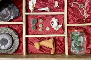 A box lined with red velvet holds ceramic art pieces in dividers.