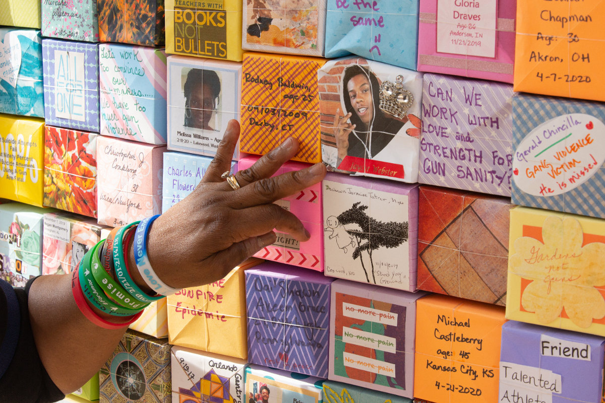 A hand pointing to squares of individual illustrations attached to a wall.