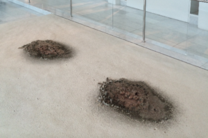 An installation of what appears to be two burned spots in the floor.